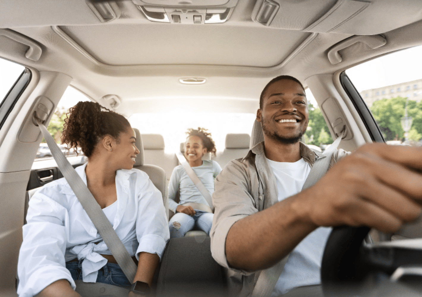 A man is driving a car and the woman sitting next to him looks in the back seat at a child in a car seat